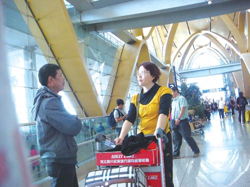 一名拉客者正在长水机场向游客推销旅游 昆明长水国际机场内有制服工作人员拉客?