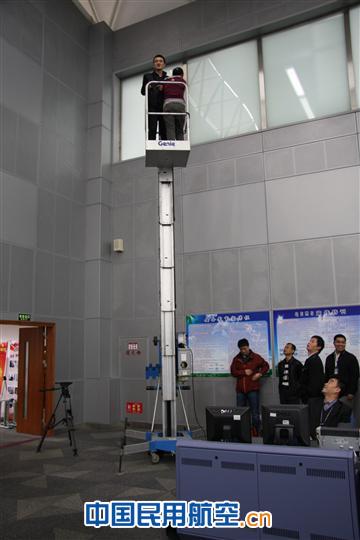 摄像记者在工作人员协助下乘云梯勘察拍摄角度 央视赴广州区管采拍《与共和国同飞》素材