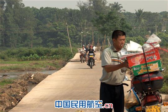 护卫阿光已在被暴雨冲毁的路段处等候我们,他接过东西放在摩托车上捆绑扎紧。 海南持续降雨 赴海口美兰机场航向台走访考察