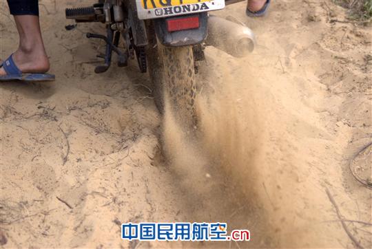 摩托车在疏松绵软的沙地里艰难转动。 海南持续降雨 赴海口美兰机场航向台走访考察